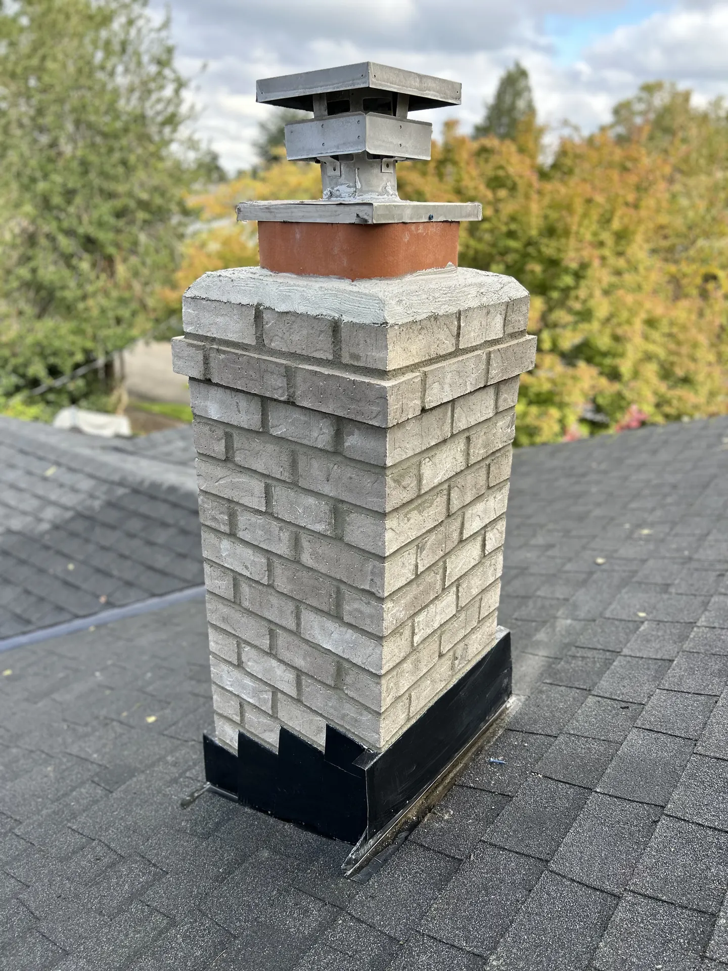 Chimney rebuild before and after: cracked white-painted masonry torn down and relaid in gray brick with a new crown